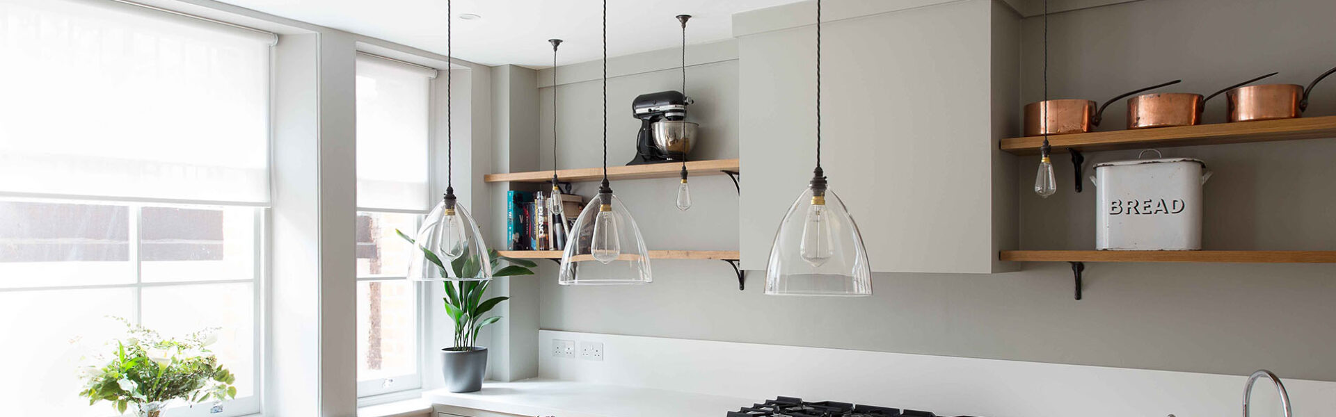 Modern kitchen with clear glass Ledbury pendant lights suspended above a countertop.