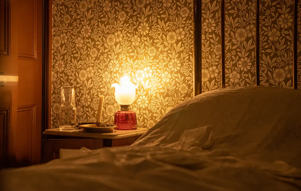 Antique table lamp casting a warm glow as bedside bedroom lighting.