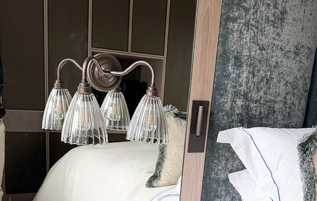 Swan neck wall lights fitted above a bed, providing elegant bedroom lighting.