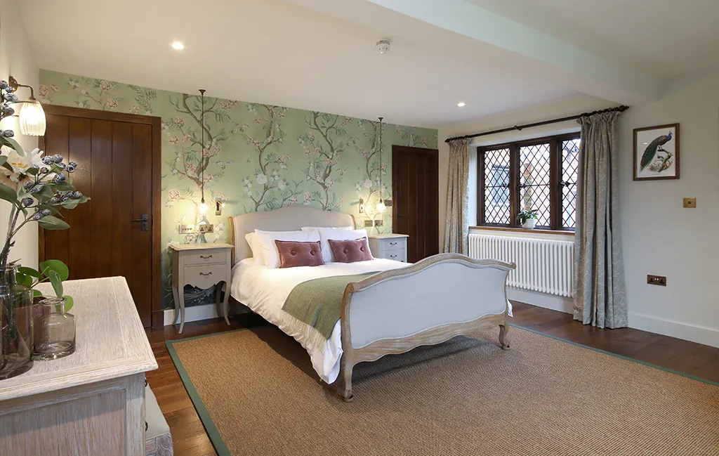 Bedroom lighting with twin pendant lights hung above bedside tables, paired with floral wallpaper.