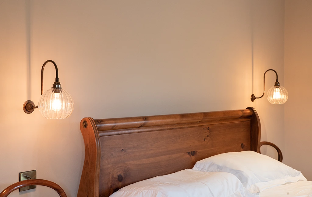 Traditional swan neck wall lights used as warm bedside bedroom lighting.